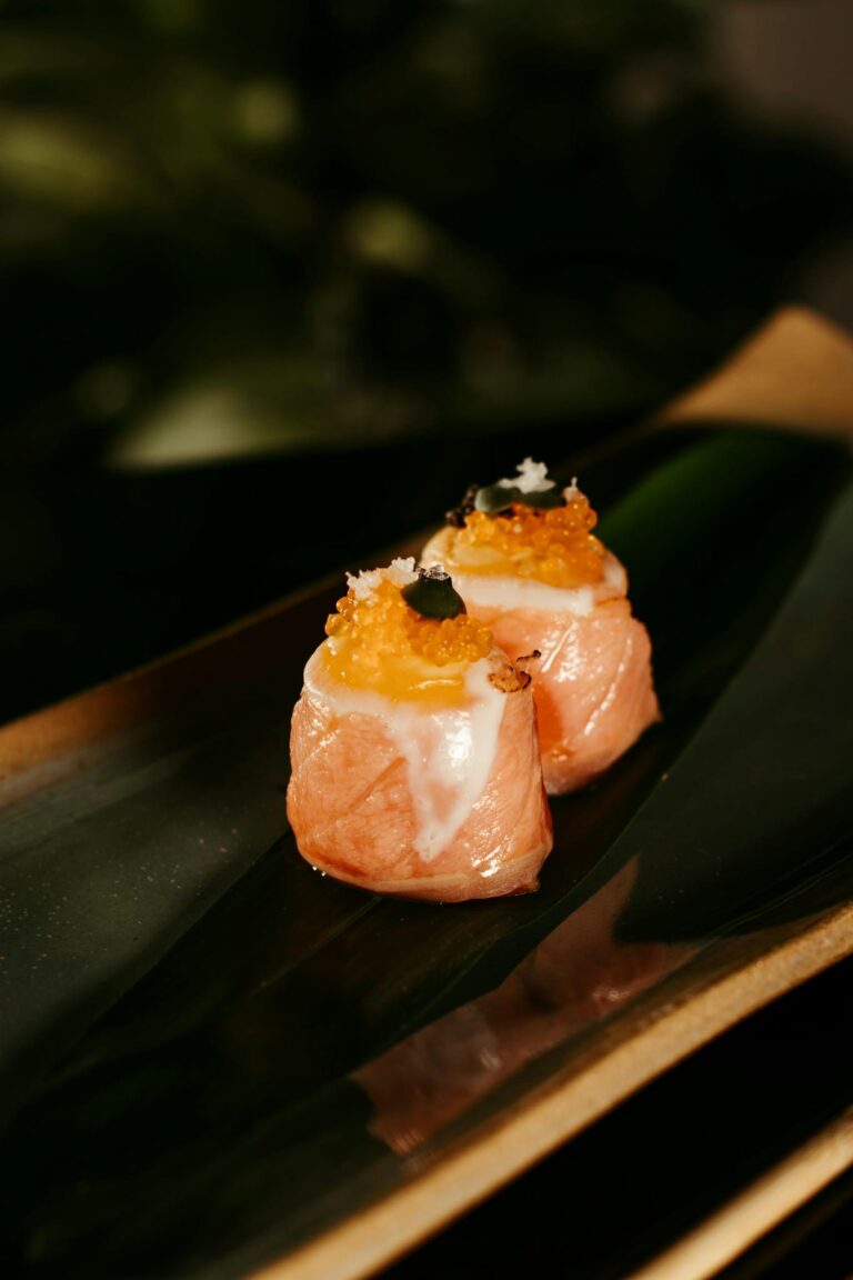 Close-up of gourmet salmon sushi rolls elegantly arranged on a dark platter with garnish.